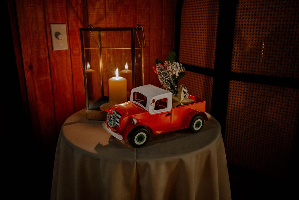 Vintage red toy truck centerpiece with candles and flowers on a draped table.