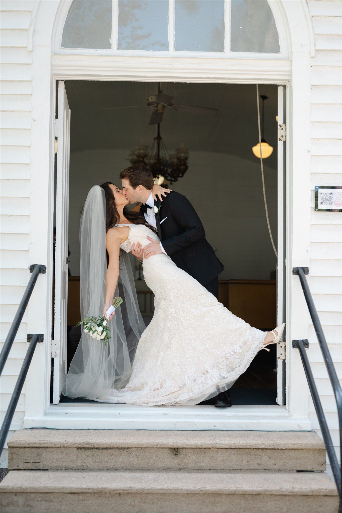 Bride and groom share a romantic dip kiss in Tomball church aisle after wedding ceremony.