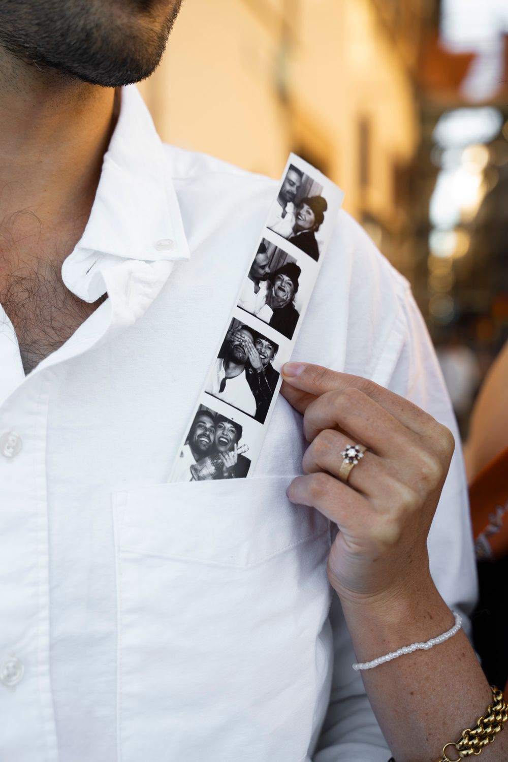 Close-up of a hand holding a black and white photo strip against a white shirt pocket.