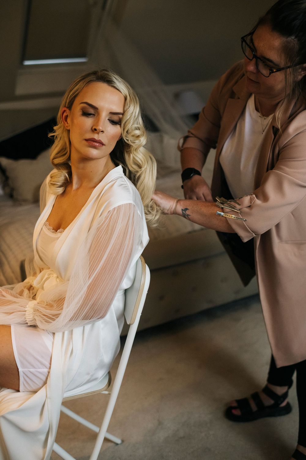 Bride getting ready in a white robe while seated in preparation room.