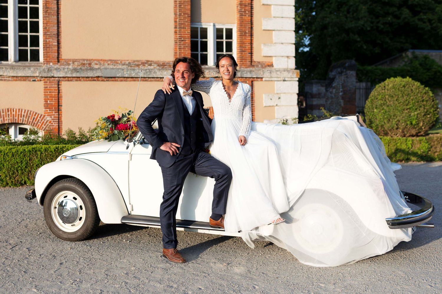 Classic white vintage car serves as backdrop for stylish wedding photos.