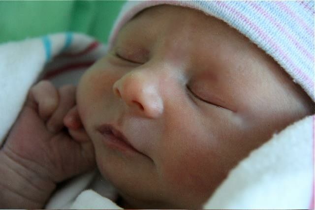 Newborn baby sleeping peacefully in a hospital blanket shortly after birth in a Fresh 48 Photo Session in Houston, TX.
