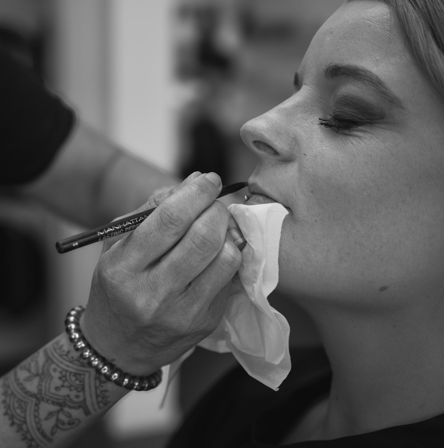 Close-up side profile of someone wiping their nose with a tissue.