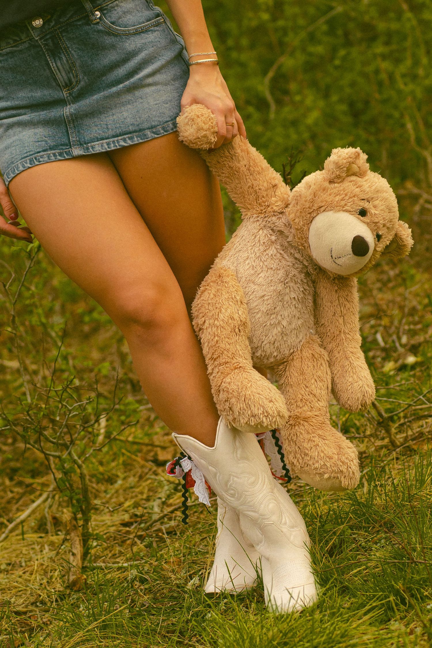 Close-up of two people holding hands in grassy field at sunset.
