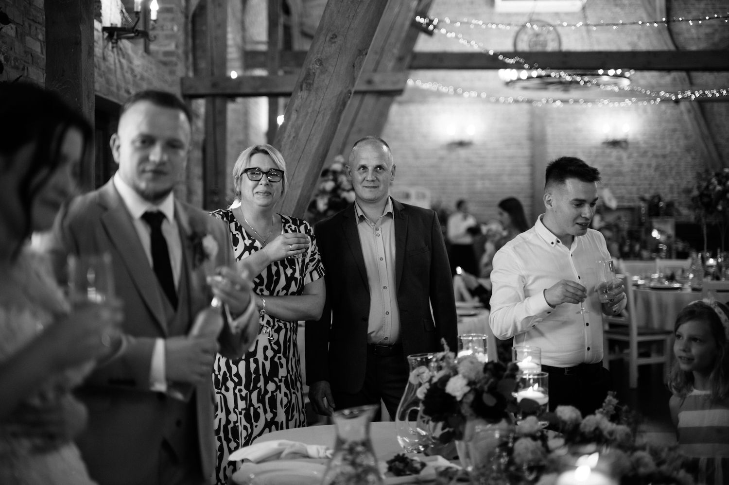 Wedding guests smiling and holding drinks in rustic barn reception venue.