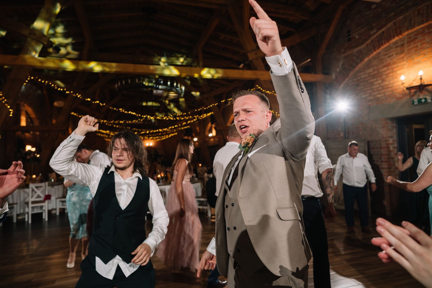 Energetic wedding guests dancing and celebrating on the dance floor at a rustic barn reception venue.