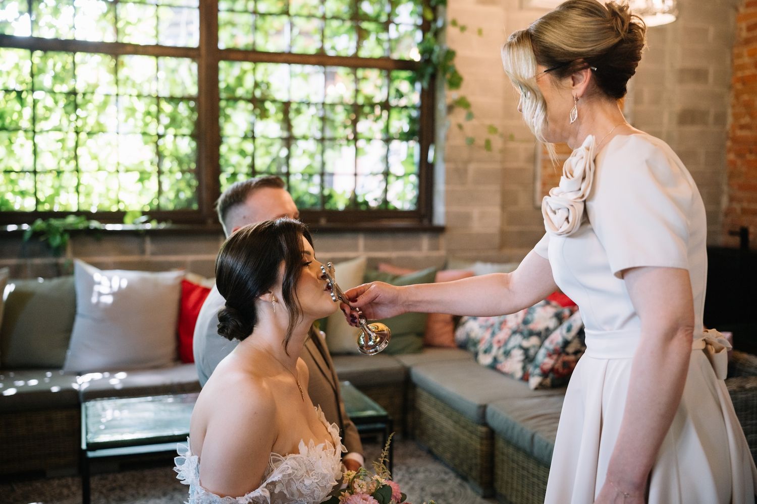 Mother adjusts brides hair accessory indoors before wedding ceremony preparation.