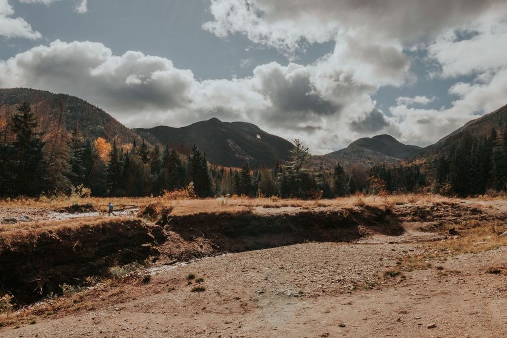 Dramatic mountain landscape panorama with cloudy skies and rugged terrain.