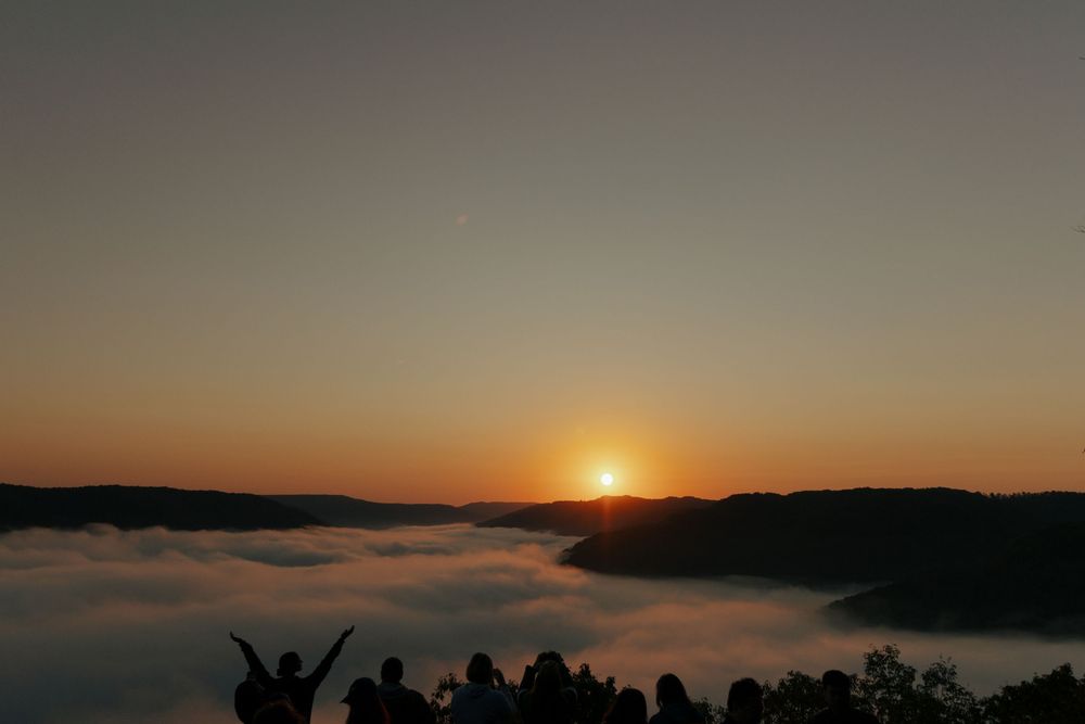 Stunning sunset panorama over mountain ridges with low-lying clouds.