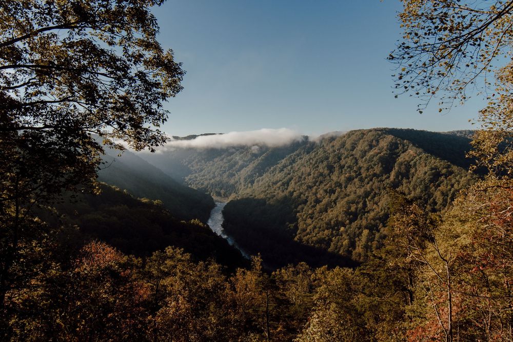 Scenic mountain vista with autumn foliage and misty valleys below.