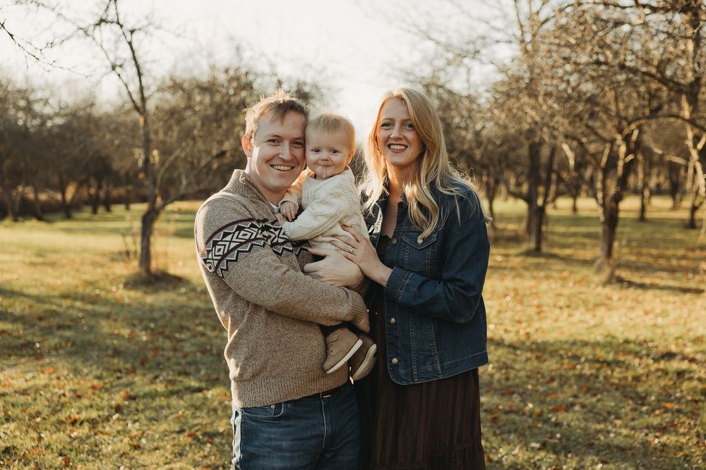 A couple shares a joyful moment together in a sunlit orchard during golden hour.