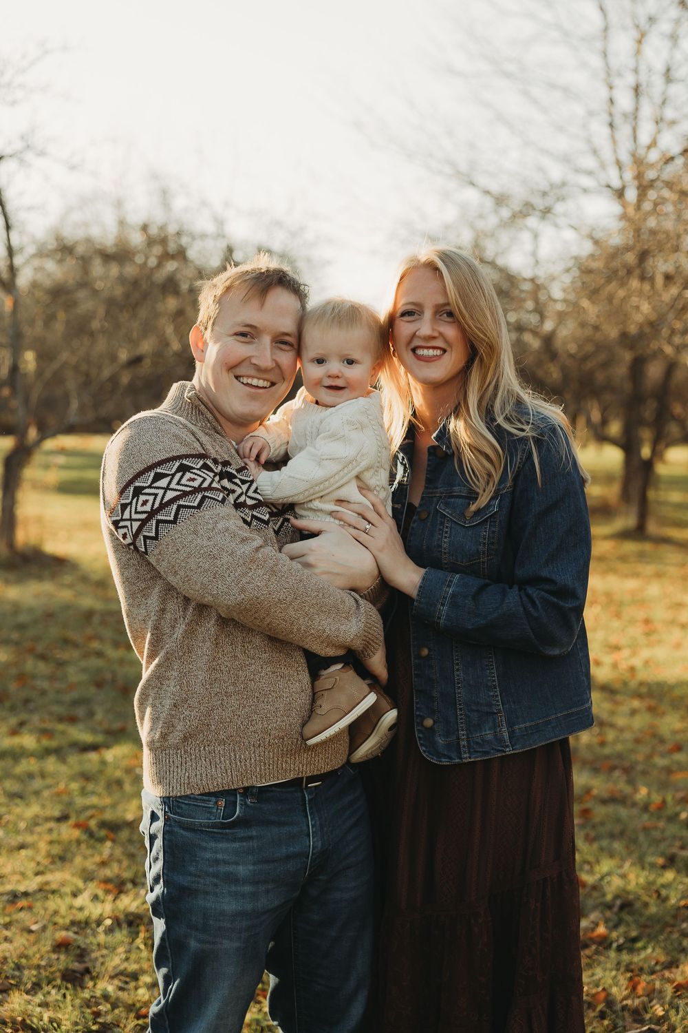 A family shares joyful moments together in a sun-drenched orchard during golden hour.