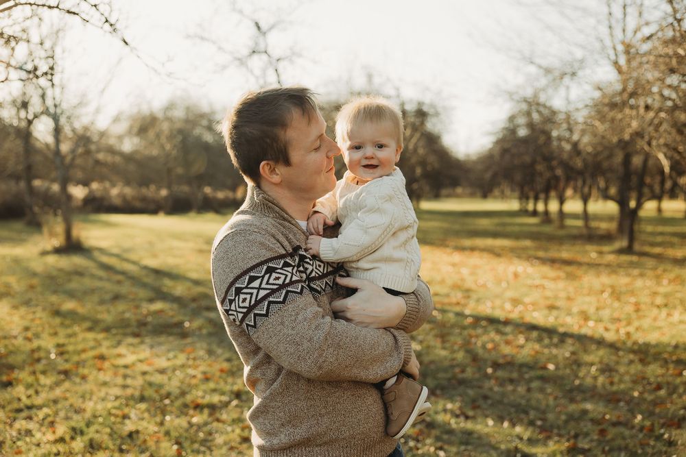A touching autumn scene shows tender family moments in a golden field at sunset.