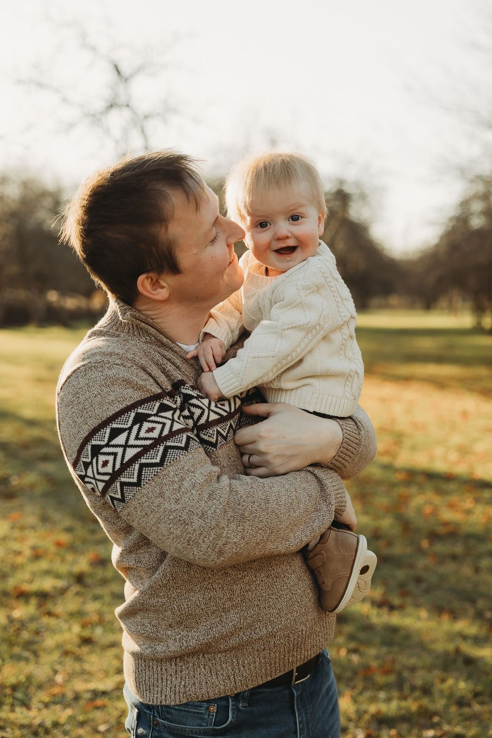 Two siblings share playful moments in a field at sunset wearing cozy sweaters on an autumn afternoon.