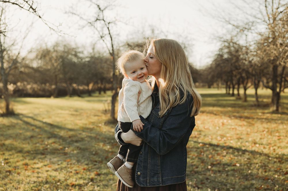 A tender moment shared between parent and child in a sunlit autumn orchard during golden hour.