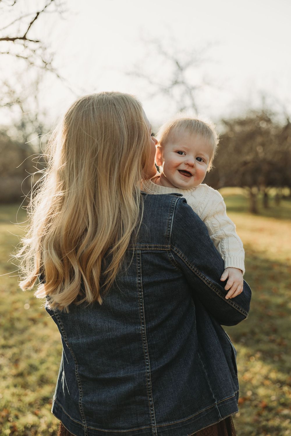 Joyful laughter and connection shared between parent and baby during golden hour in a fall outdoor setting.