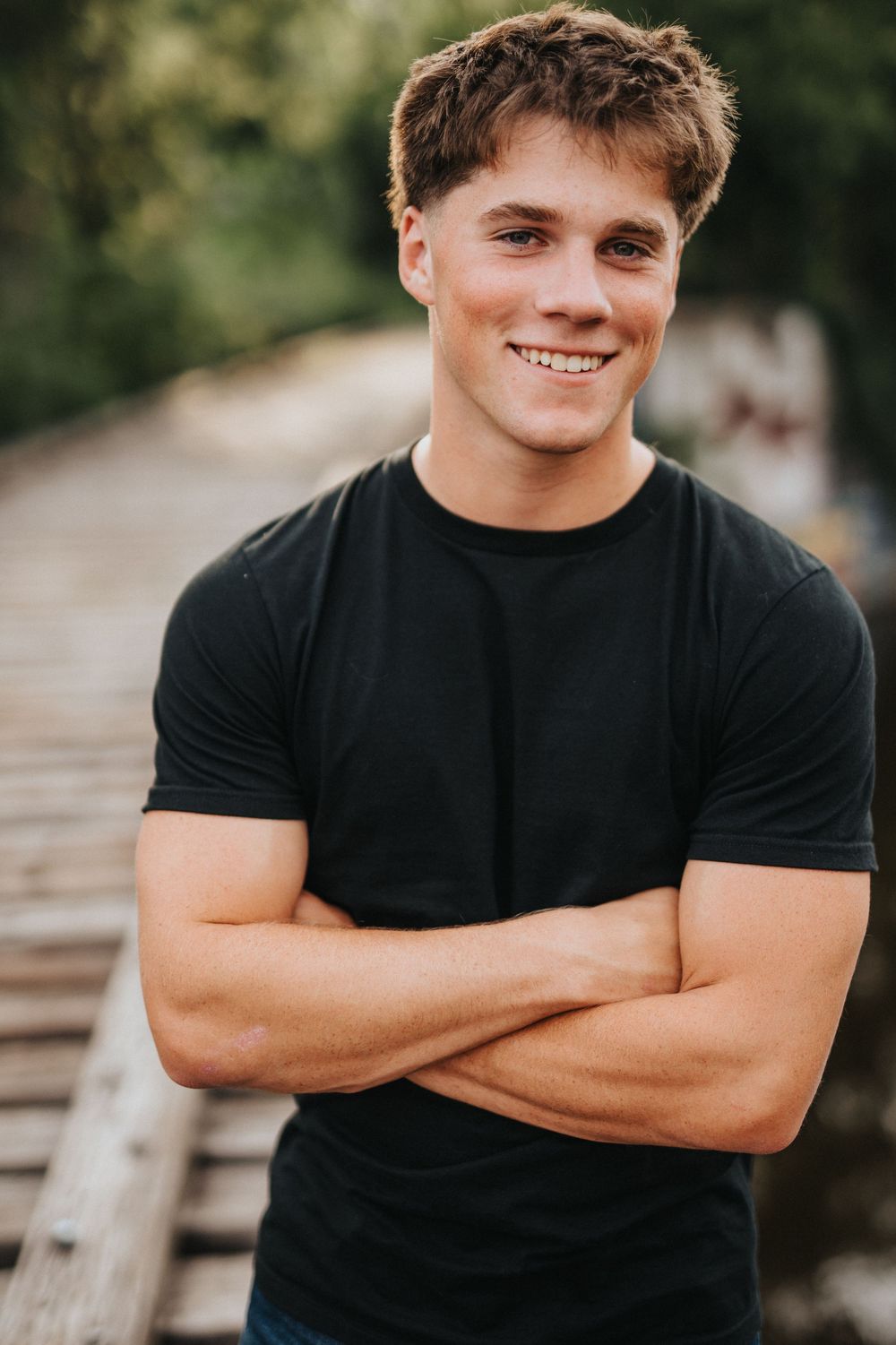 A series of outdoor portrait shots showing someone in a black t-shirt with crossed arms and a casual pose.