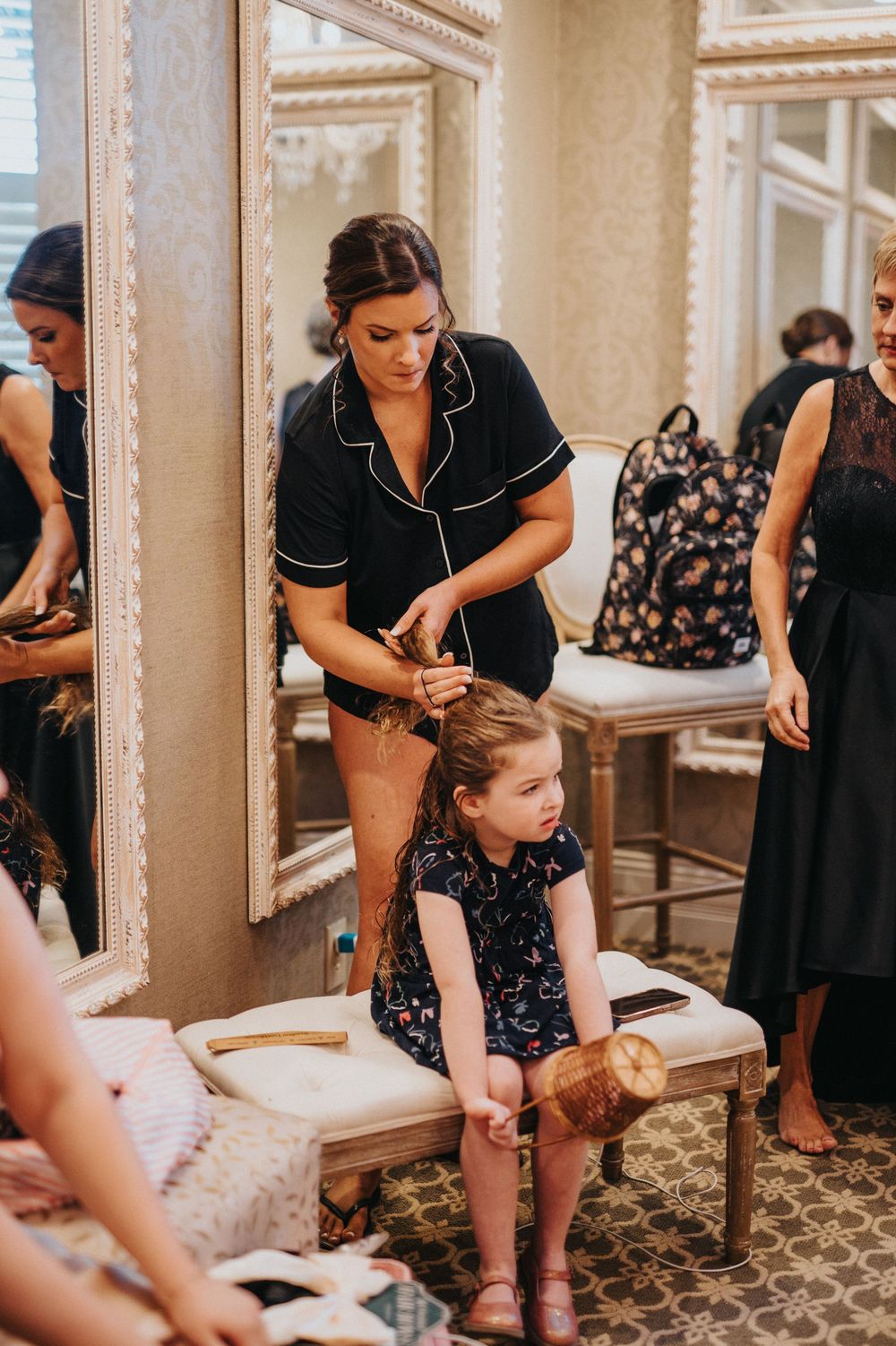 Stylist works on hair preparation in elegant dressing room with ornate mirrors and decor.