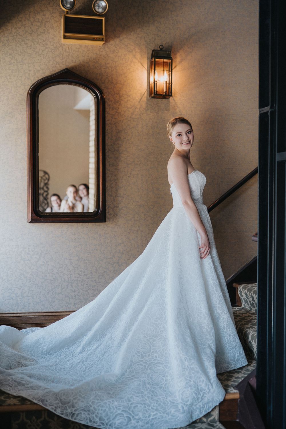 A stunning white wedding gown with intricate lace details and a flowing train photographed in an elegant indoor setting.