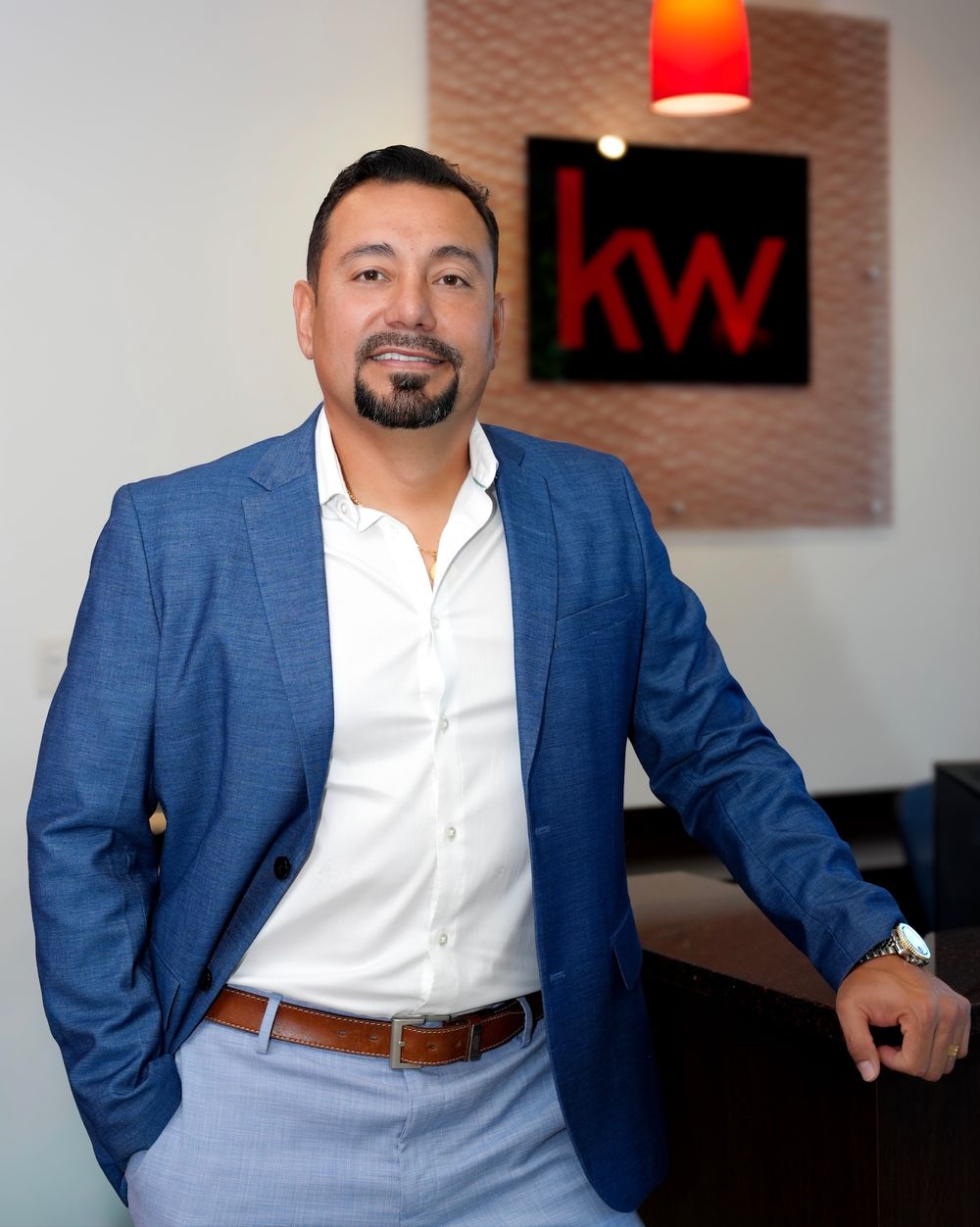 Professional man in blue blazer poses confidently in front of Keller Williams KW real estate office. kw realty headshots. Tampa Bay photos