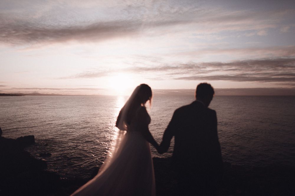 Brautpaar als Silhouette bei Sonnenuntergang am Meer – intime Hochzeitsstimmung zwischen Licht, Weite und Nähe.