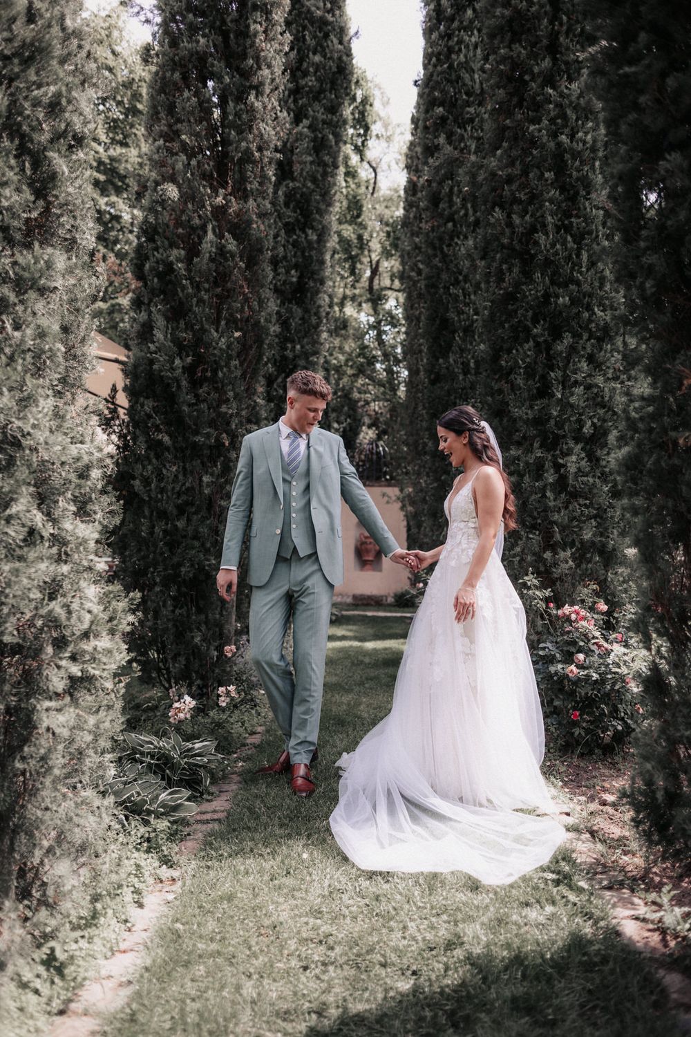 Brautpaar geht Hand in Hand durch den Garten im Morrhof – elegantes Paarporträt beim First Look in natürlicher, ruhiger Atmosphäre.