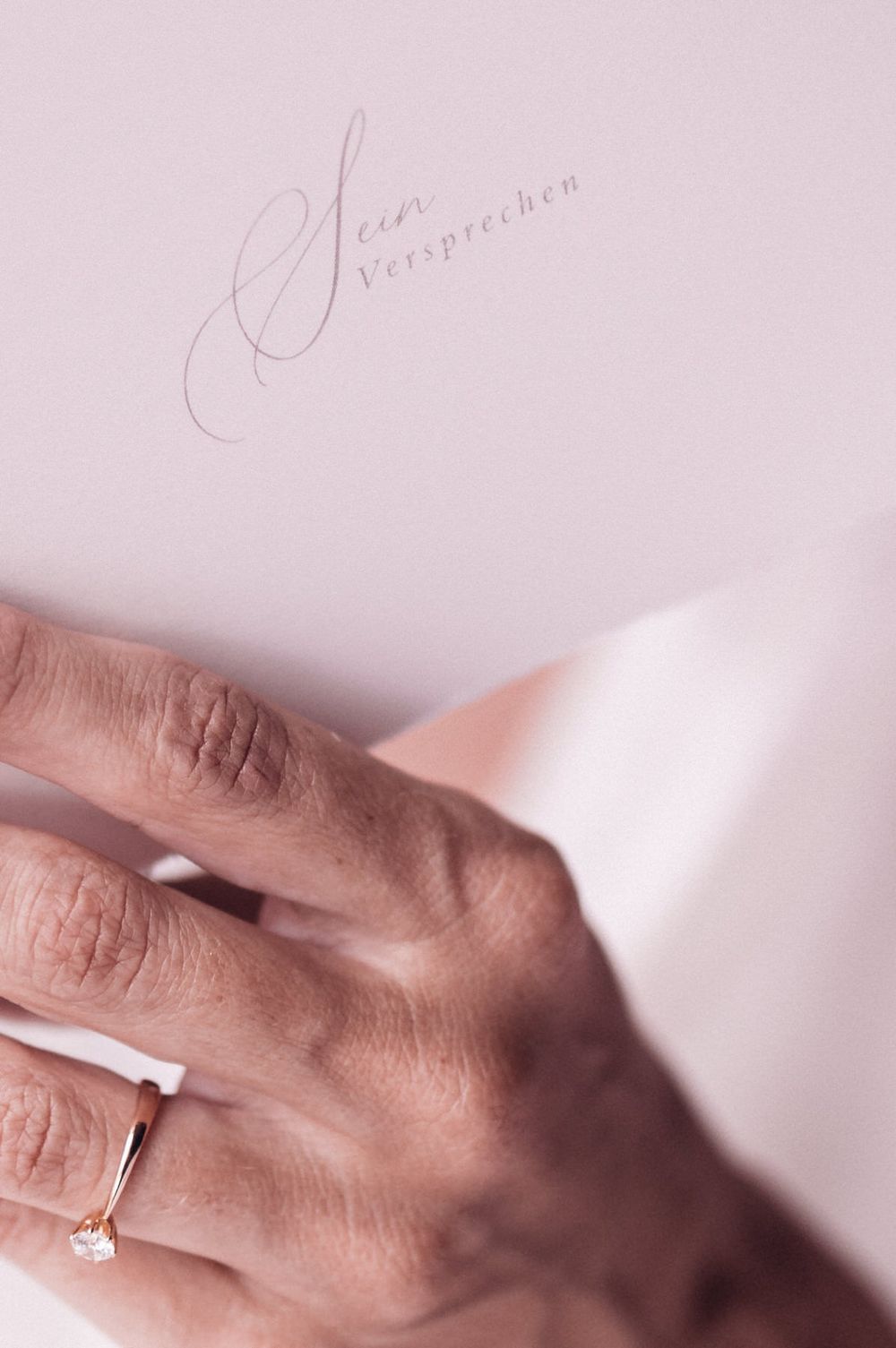 Detailaufnahme eines Verlobungsrings auf einer Hand, daneben Schriftzug „Sein Versprechen“ – leise, intime Hochzeitsästhetik.