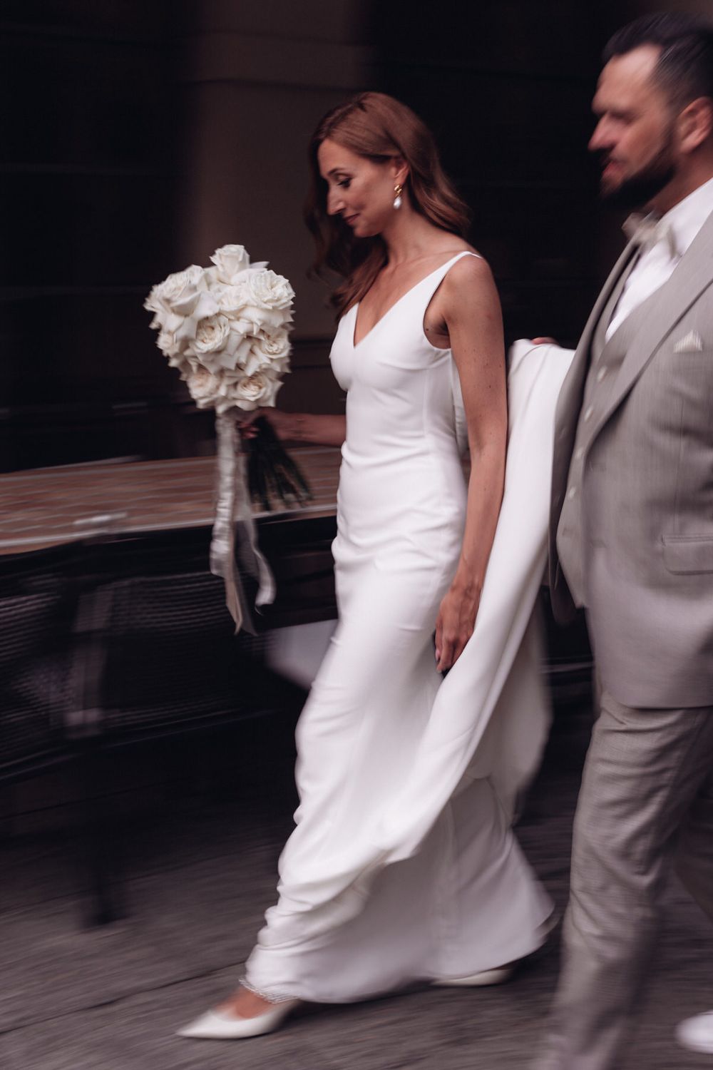 Braut auf dem Weg zur Trauung, begleitet vom Bräutigam – zeitlose Eleganz, Bewegung und moderne Hochzeitsfotografie.