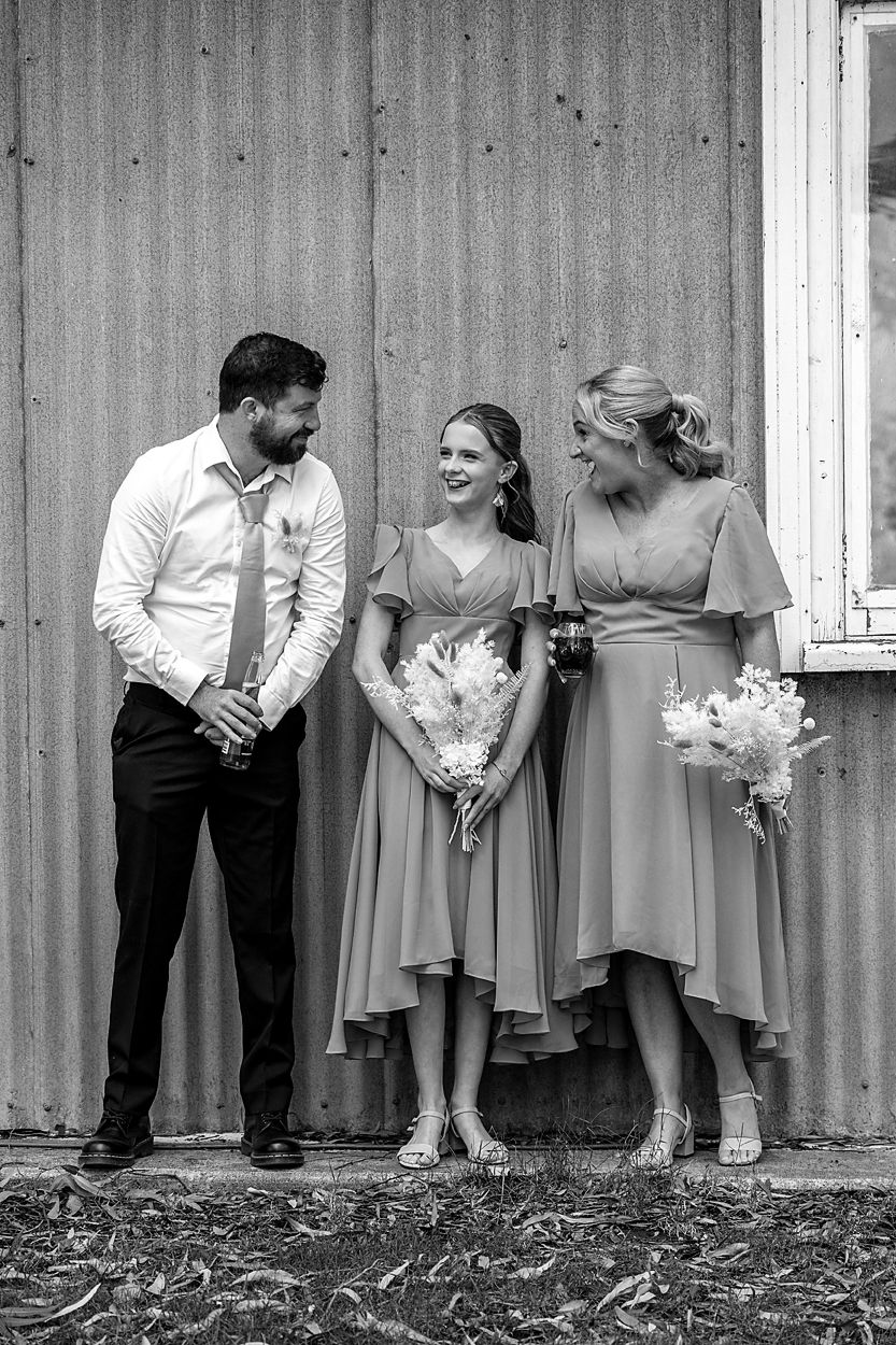 A black and white artistic photo series showing wedding party members lined up against a rustic wall.