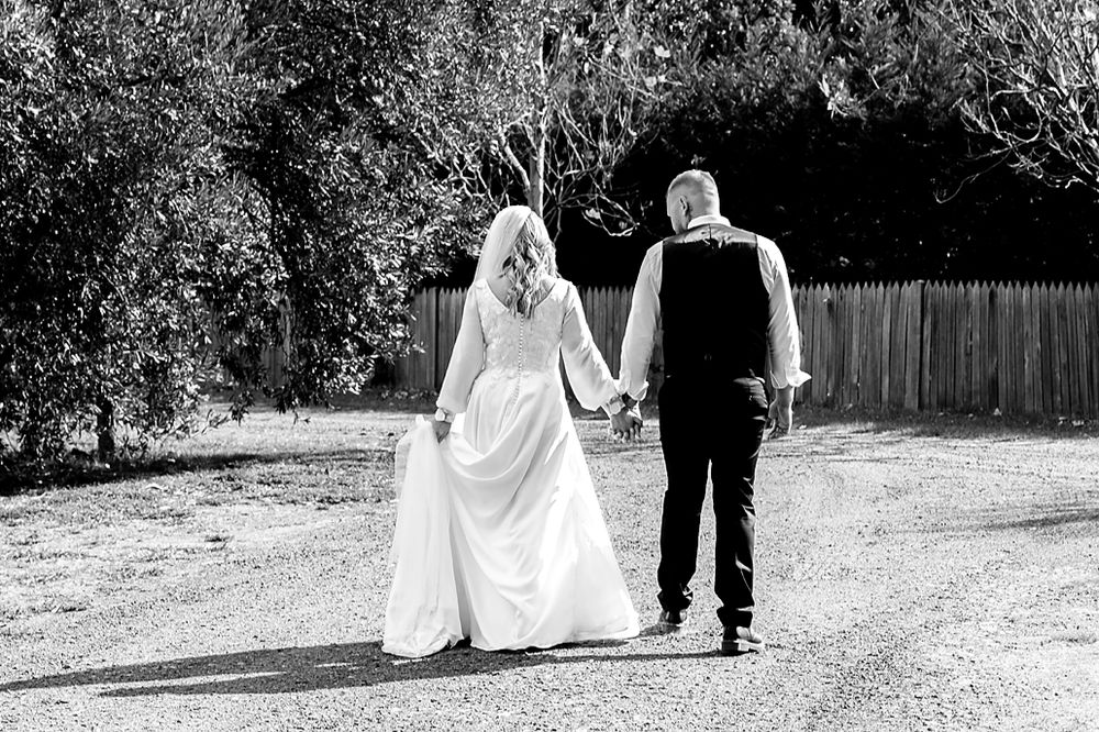 A series of black and white wedding photos showing a couple walking together on a path.