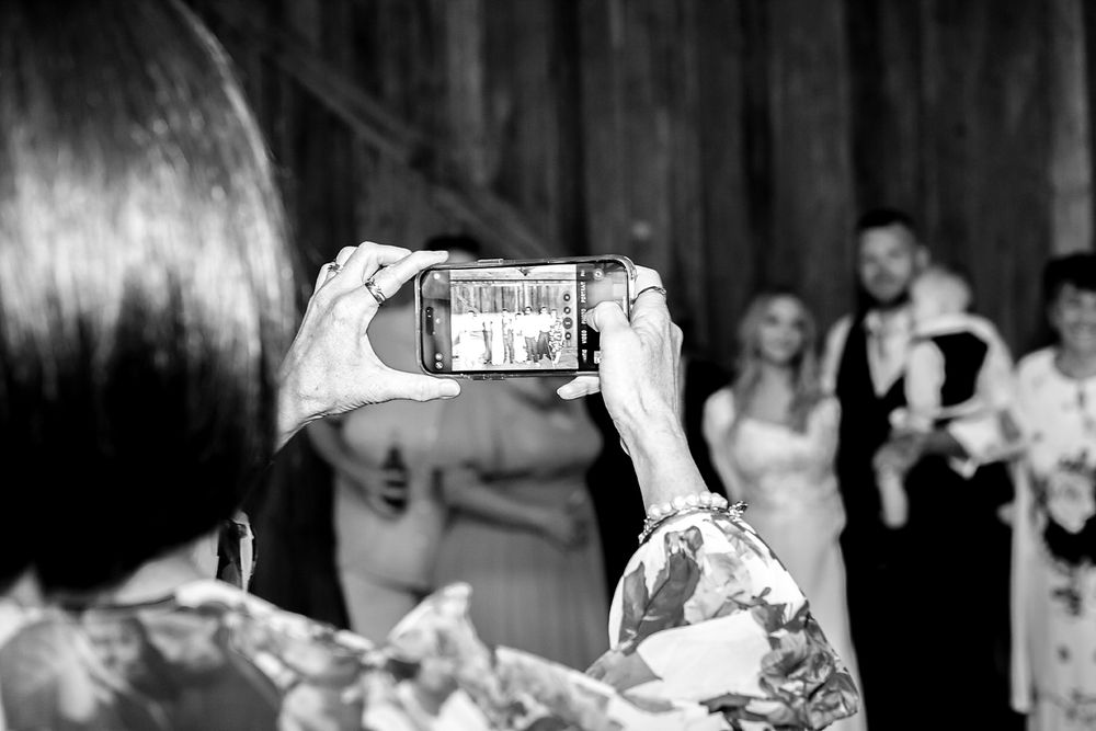 A person takes a photo on their smartphone at a formal event in black and white photography.