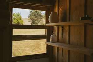 Sunlit windows in wooden cabin interior showing countryside view.
