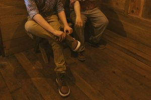 People gathered on wooden floor of rustic cabin interior.