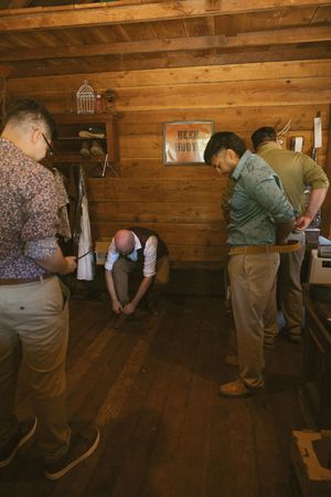 People gathered in rustic cabin with wooden walls and floors during event.