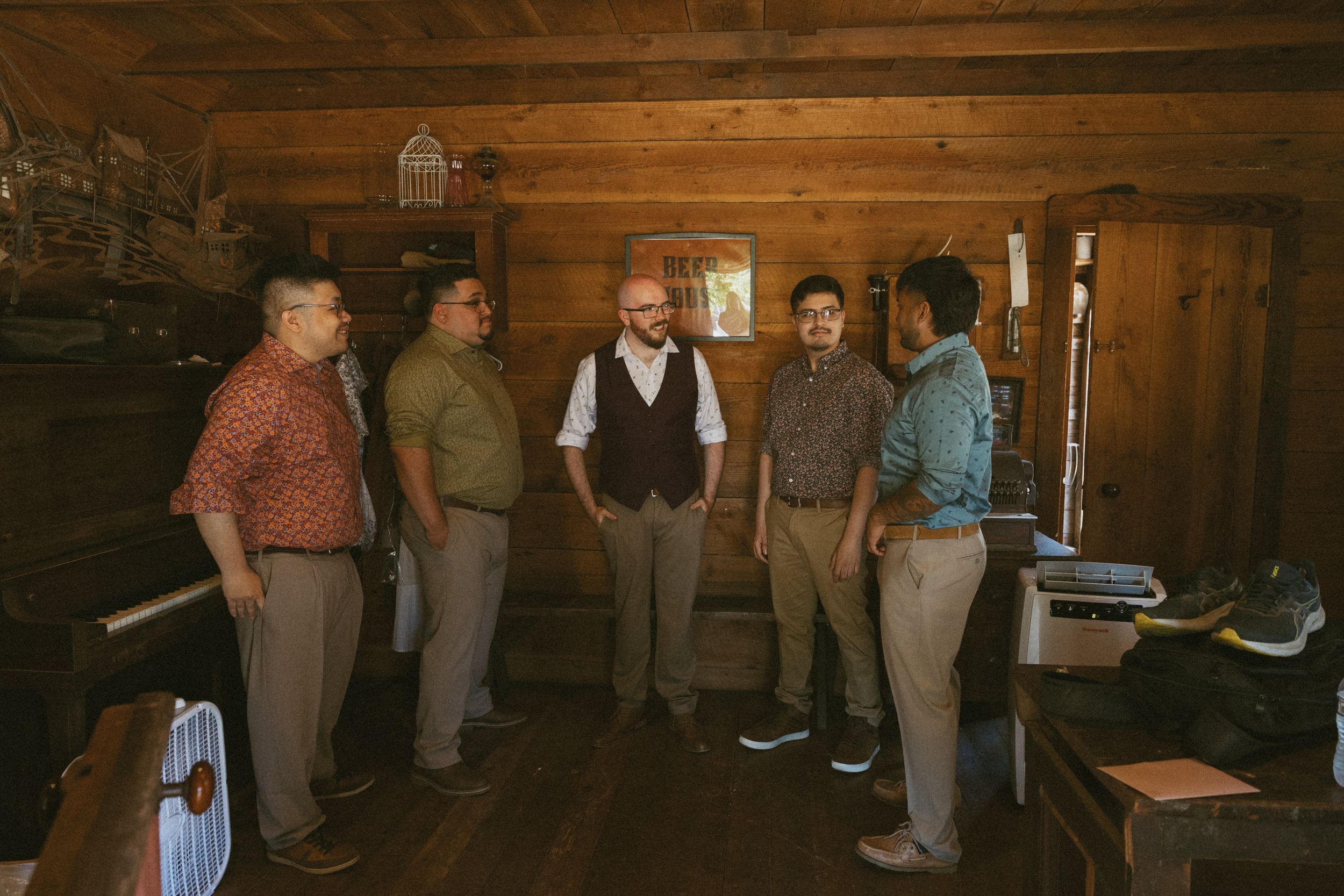 People gathered inside a rustic log cabin with wooden walls and floors.