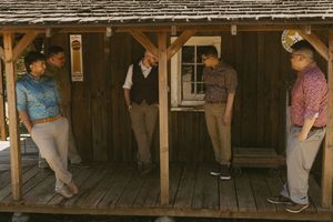 Wide view of people inside a covered wooden porch or cabin structure.