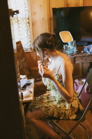Person working on detailed crafts at a wooden table in warm lighting.