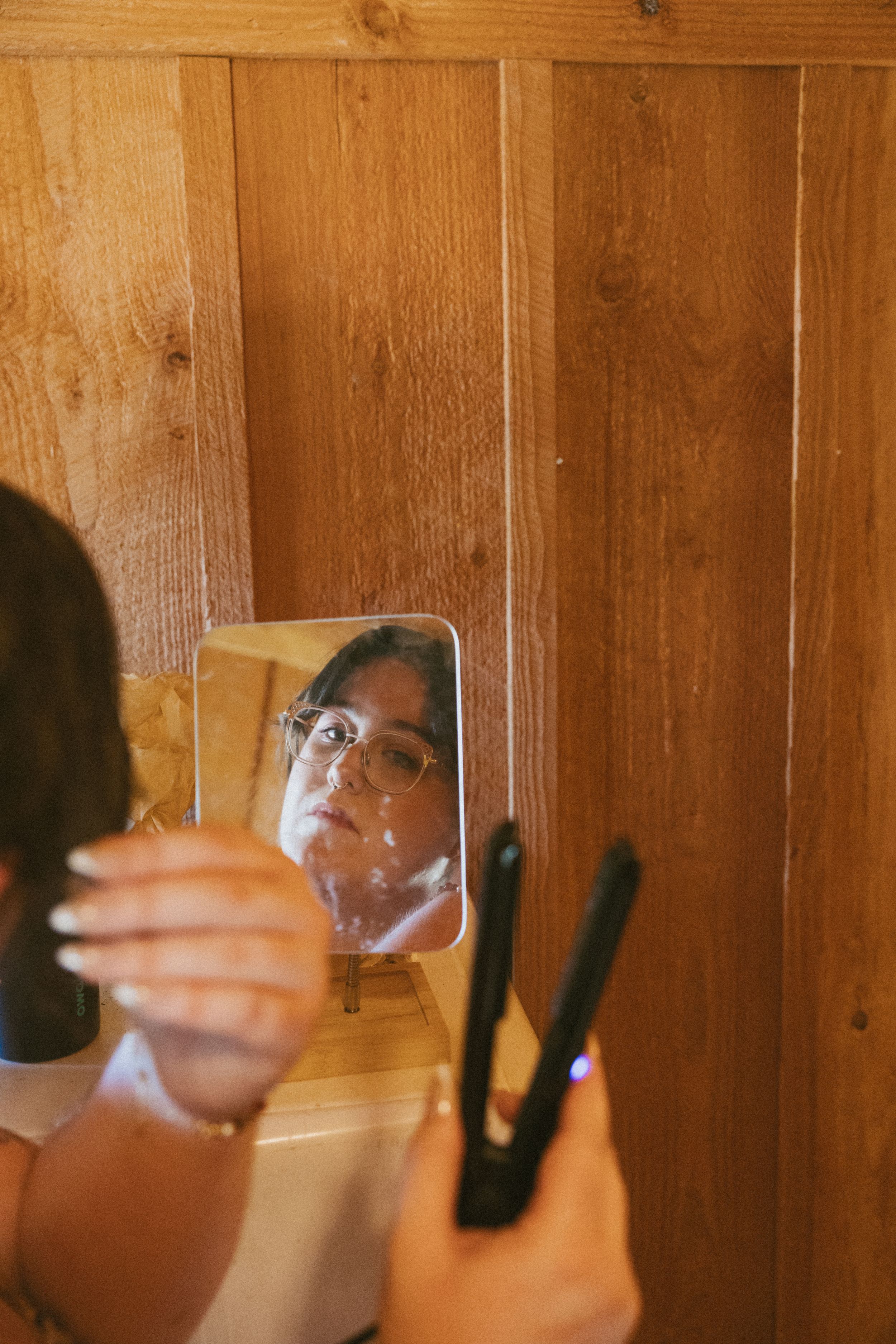 A series of reflections in small square mirrors mounted on a wooden wall creates a fragmented visual effect.