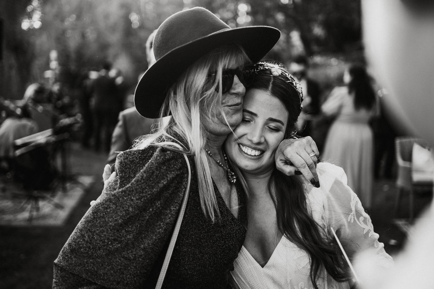Joyful wedding guests sharing laughs during outdoor celebration.
