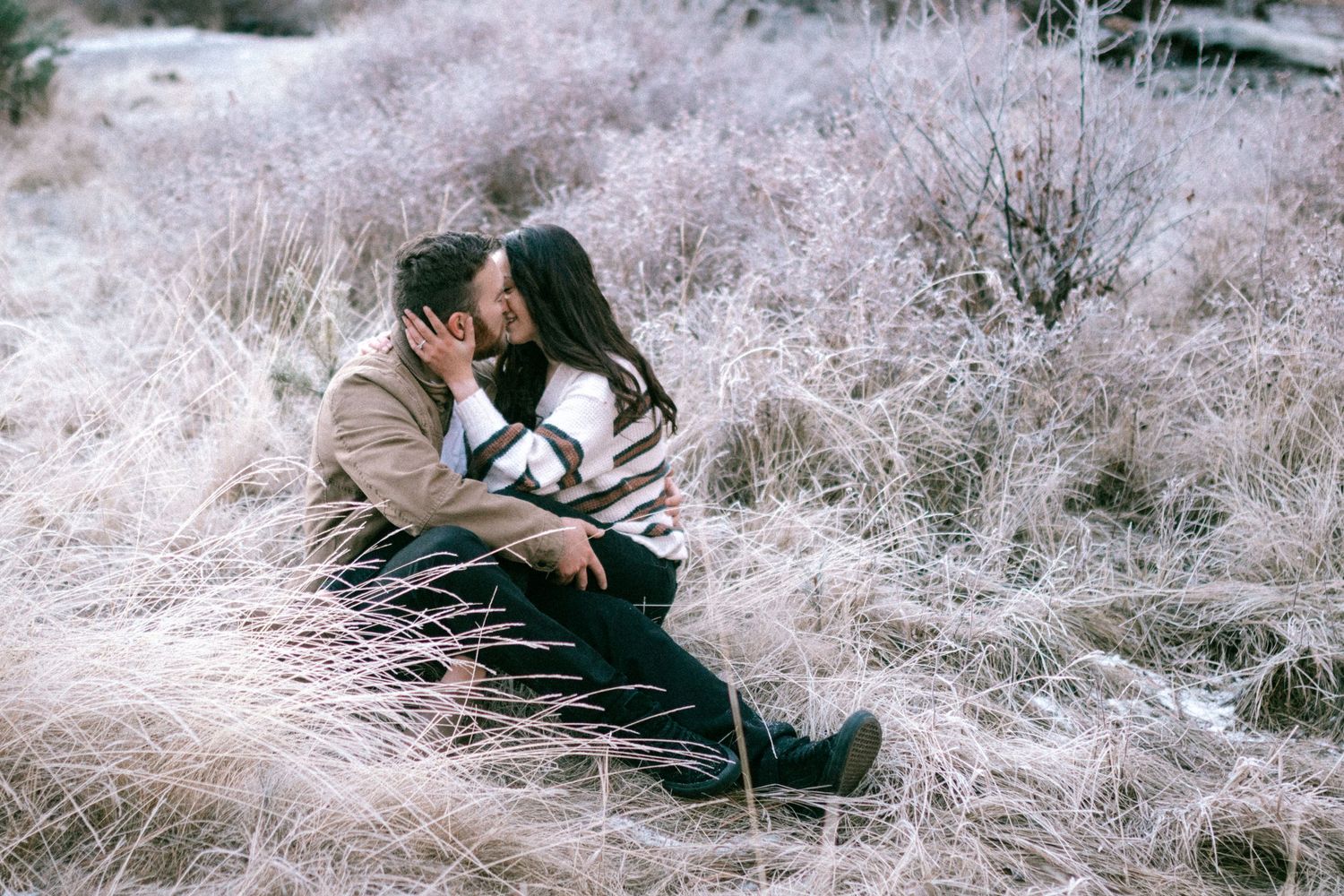 A person sits in a field of white, wispy grass creating a dreamy, ethereal outdoor scene.