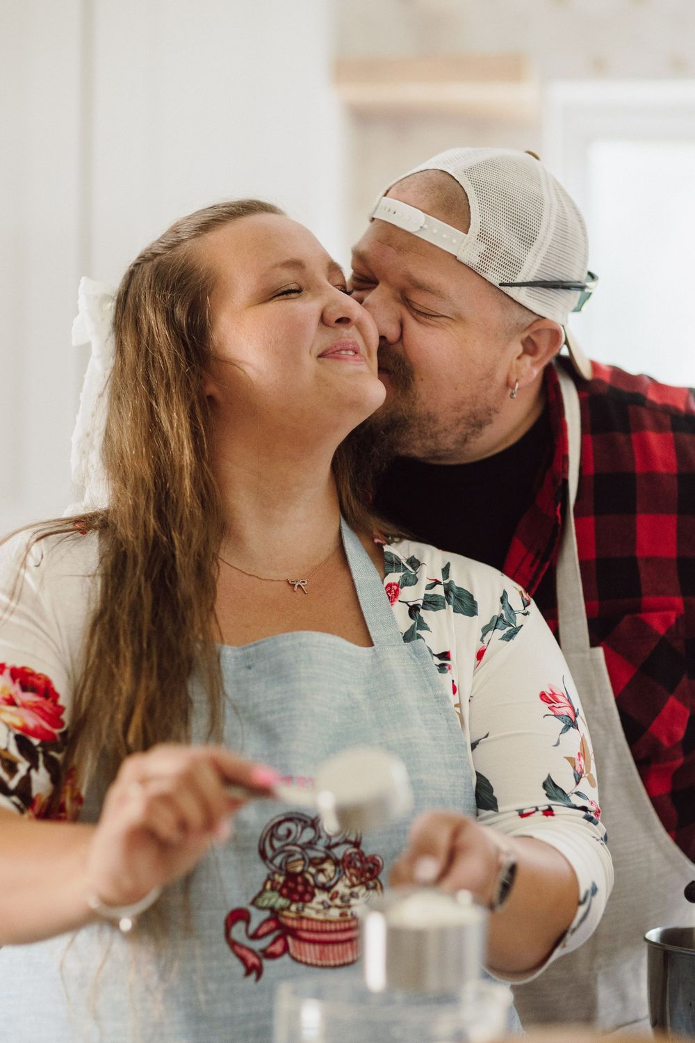 A sweet moment shared between a couple in a bright kitchen while enjoying treats.