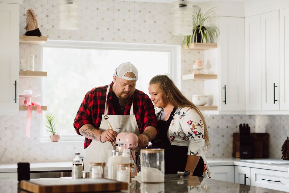 Couple sharing intimate moments while baking in a sunlit modern kitchen.