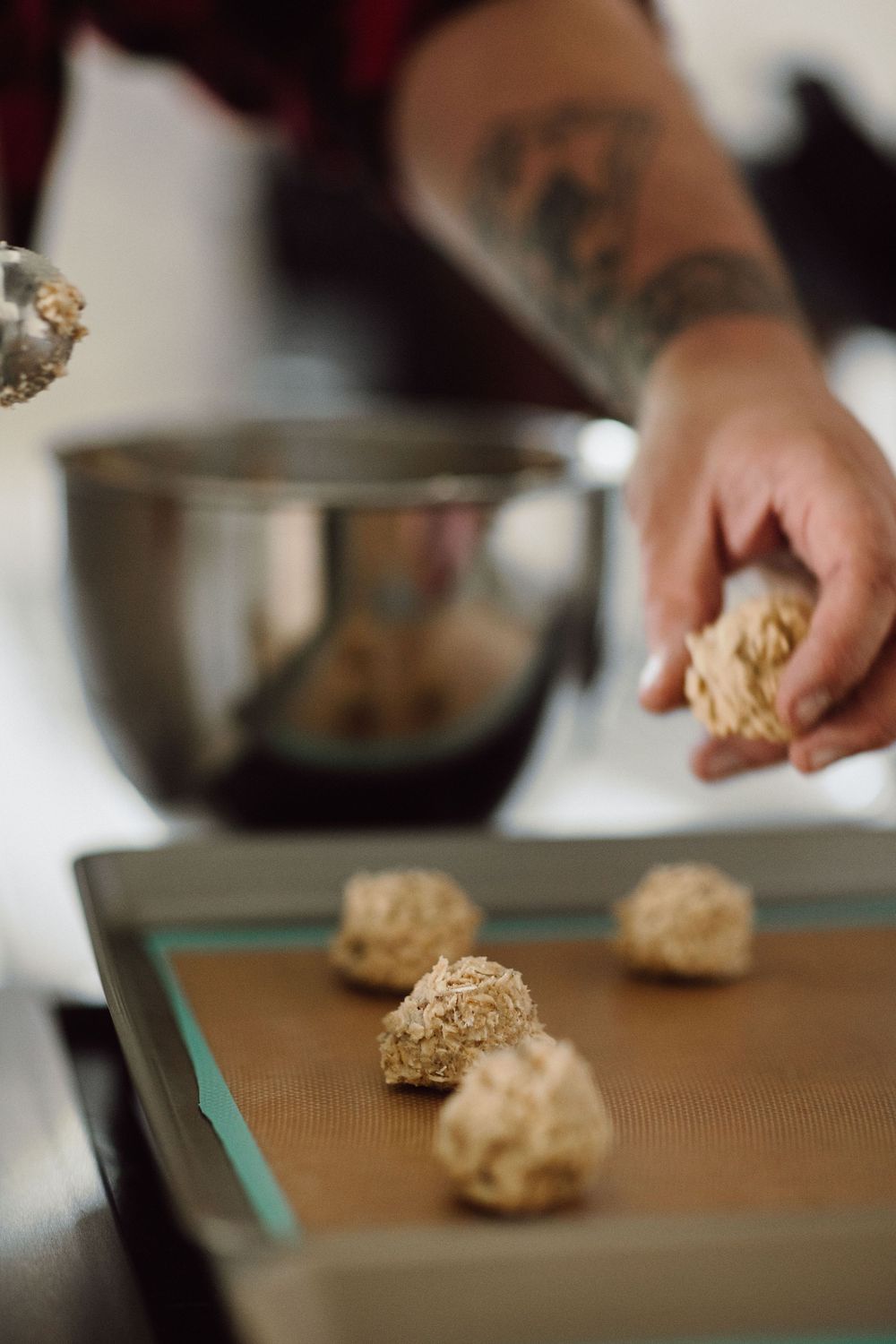 Close-up of hands forming cookie dough on a wooden cutting board.