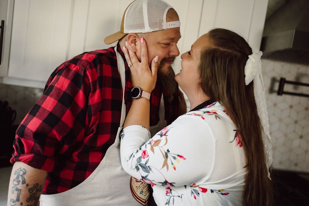 Couple sharing an intimate moment in a bright kitchen setting.