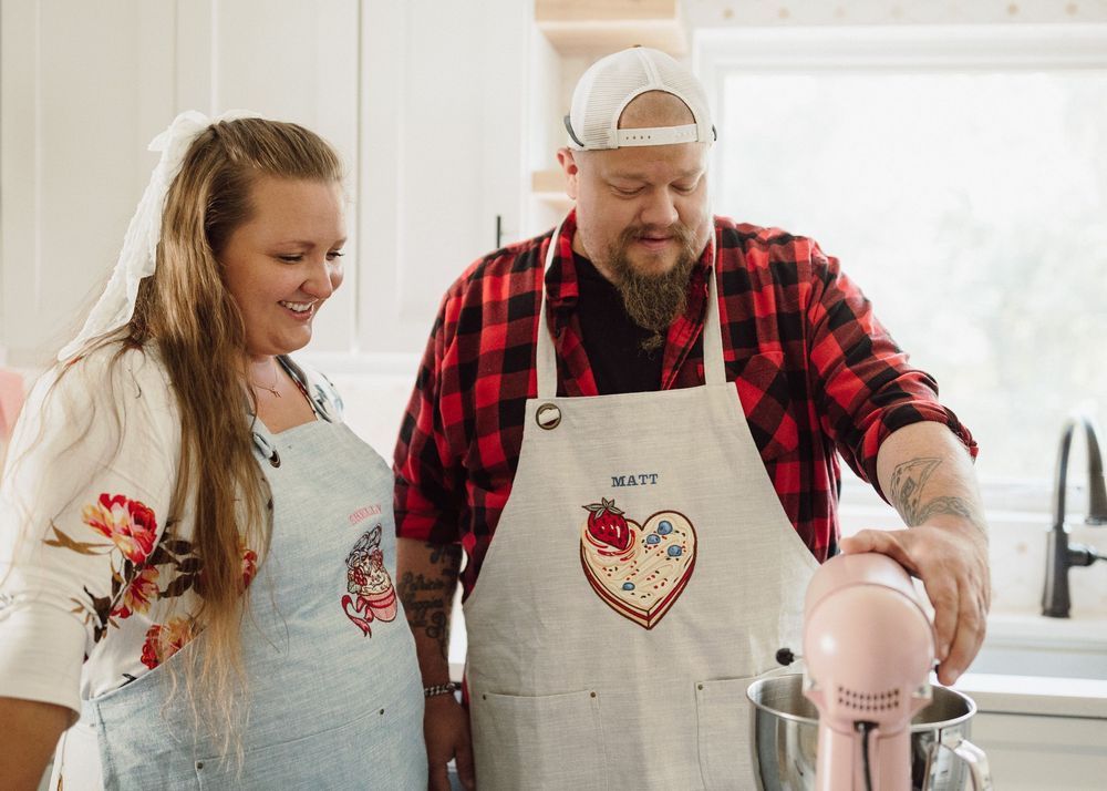 People wearing aprons work together preparing food in a white contemporary kitchen.