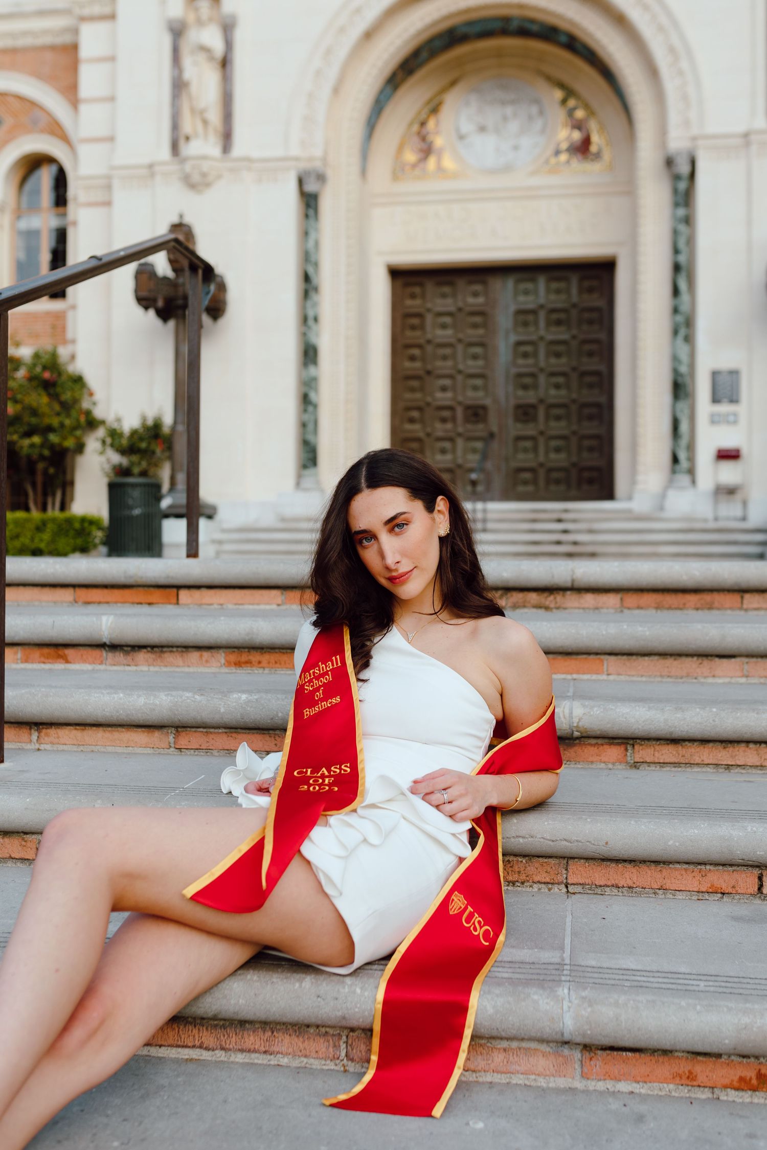 A graduate in a red sash poses for her graduation photos; taken by a Bay Area Graduation Photographer.
