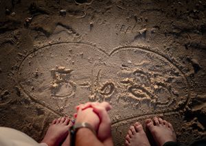 Time-lapse sequence of bare feet stepping into wet sand at the beach, leaving footprints in a row.