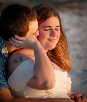 A tender moment between two people embracing on a beach during golden hour.