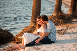 Couple enjoying a romantic sunset moment together on a sandy beach near the water's edge.