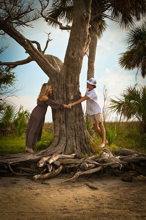 A sequence of photos showing someone playfully leaning against a large tree trunk on a sandy beach with palm trees.